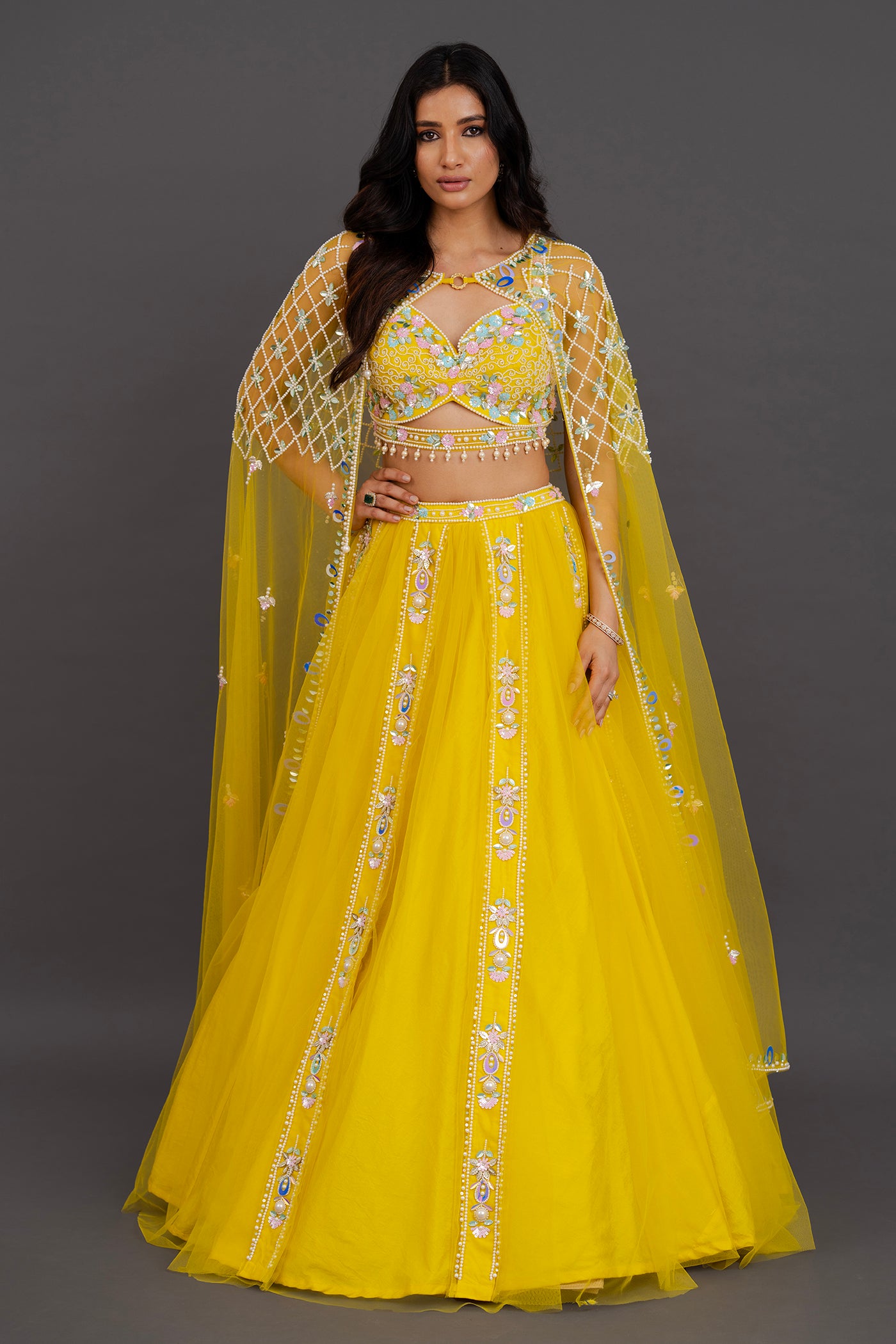 Vibrant yellow net lehenga with floor length cape