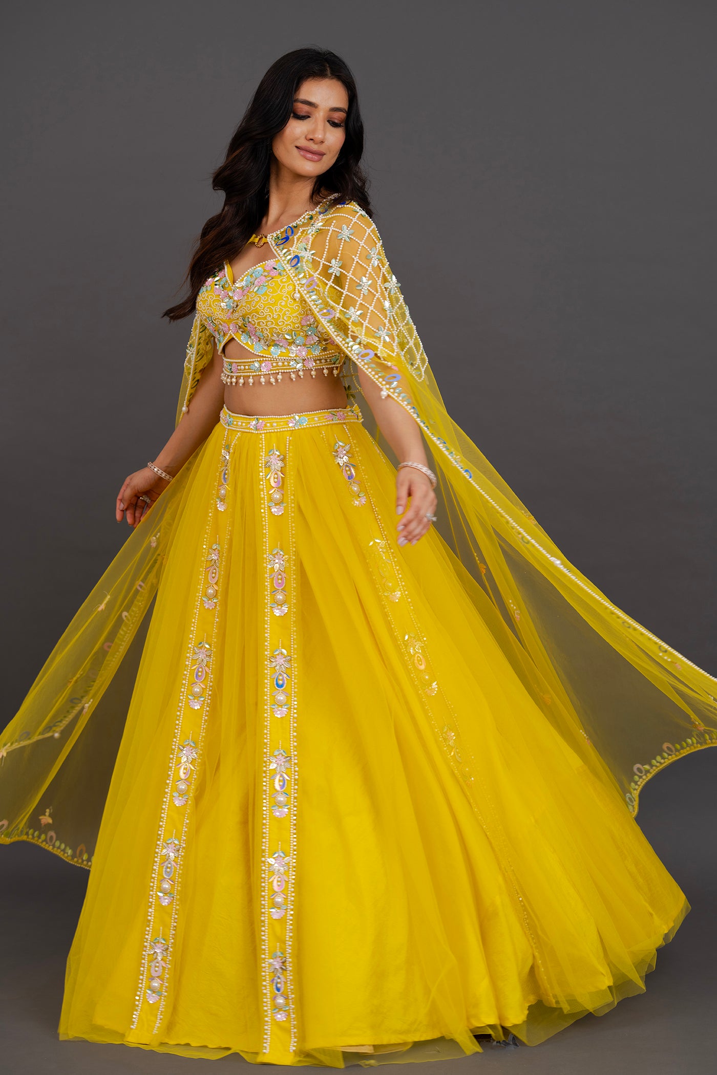 Vibrant yellow net lehenga with floor length cape